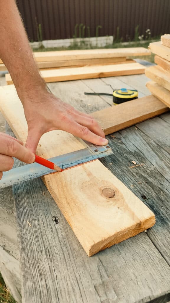 Cropped hands of male carpenter marking on plank with pencil